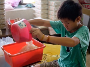 忙著碾米出貨的季節，權祐幫忙秤重，讓爸爸加快包裝速度。
