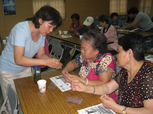 資深班員陳麗姿（左）教其他班員如何將種籽串珠（本圖由台東縣農會提供）